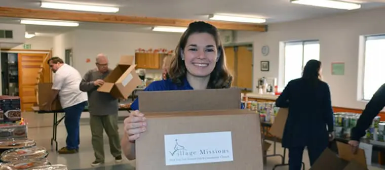 Makenzie is pictured holding a box with a VM logo during a community engagement event.