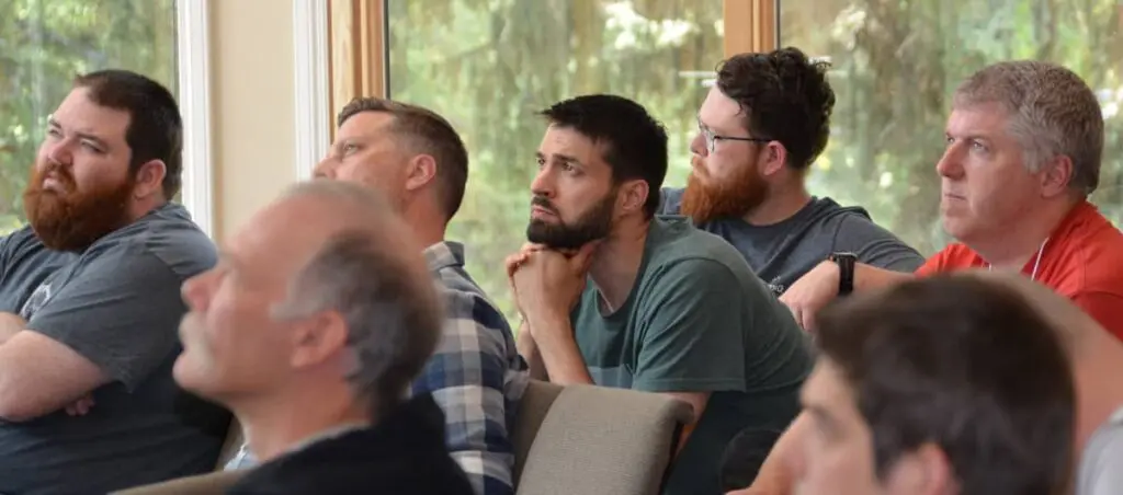 A group of men from country churches listens intently to a speaker.