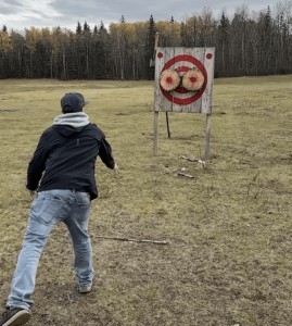 A man from Meadowbrook church throws an axe at a target.