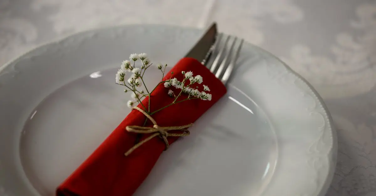 Elegant table setting with a red napkin, cutlery, and white flowers for a classy dining experience.